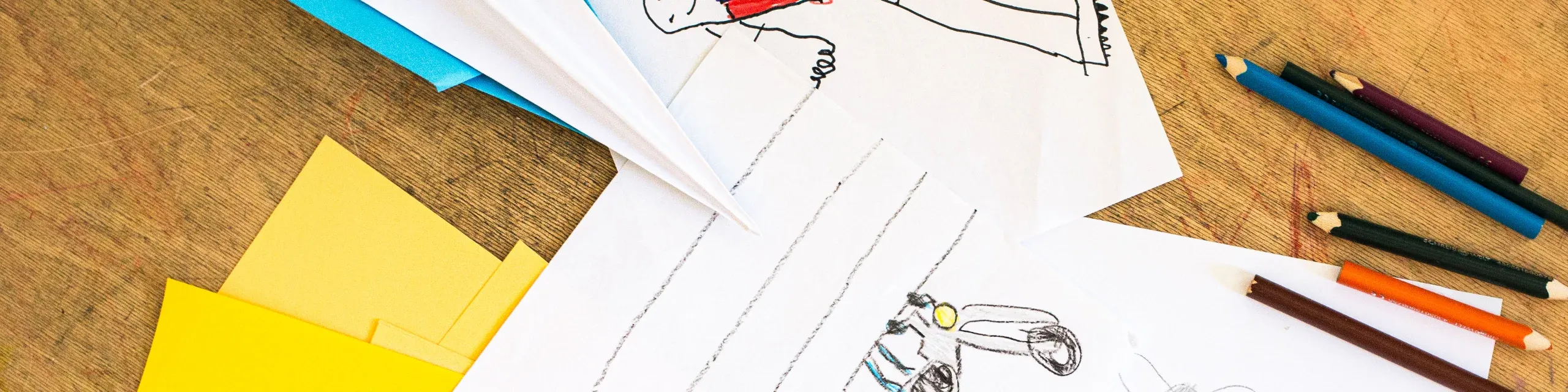 Dibujos de niños, lápices y avión de papel
